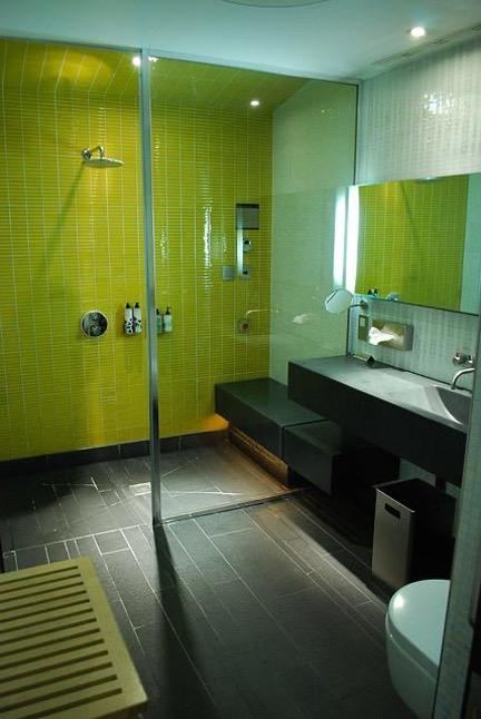 A bathroom scene with a bottle on a small shower shelf.