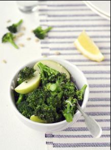 A bowl of broccoli with a spoon resting inside it.